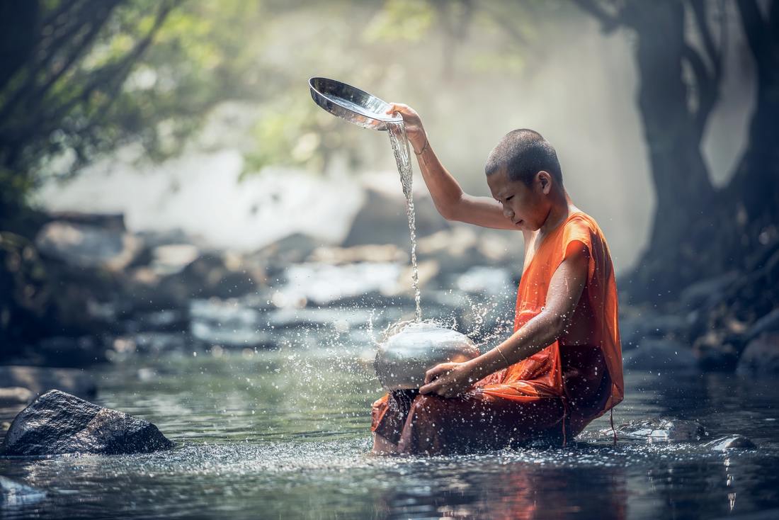 young forest monk meditating on water